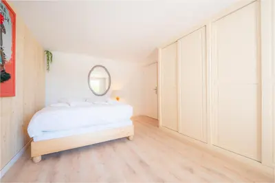 a white bedroom with a bed and a mirror at Ambiance sudiste , piscine, boule, farniente AG in Carcassonne