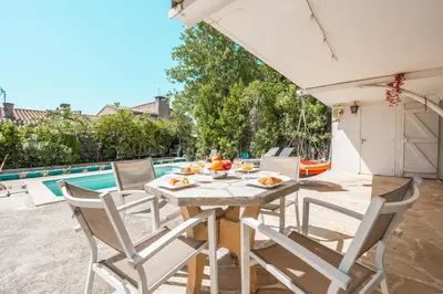 a patio with a table and chairs and a pool at Ambiance sudiste , piscine, boule, farniente AG in Carcassonne