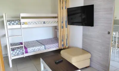 a small room with bunk beds and a flat screen tv at Chez Rosa in Pradelles-Cabardès