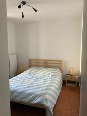 a bedroom with a bed and a night stand with a lamp at Grand T2 à Gruissan, calme, vue sur le port in Gruissan