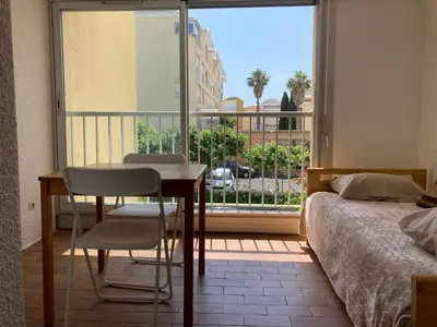 a bedroom with a bed and a table and a window at Grand T2 à Gruissan, calme, vue sur le port in Gruissan