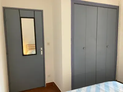 a bedroom with a gray door and a mirror at Grand T2 à Gruissan, calme, vue sur le port in Gruissan
