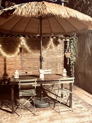 a table with an umbrella and two chairs under it at Maison de charme in Fontrieu