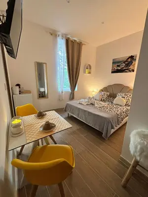 a bedroom with a bed and a table and a chair at La Perle in Narbonne