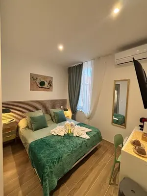 a room with a bed and a desk and a television at La Jade in Narbonne