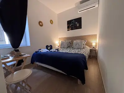 a bedroom with two beds and a table and a window at La Topaze in Narbonne