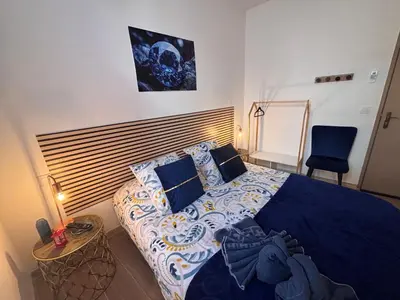 a bedroom with a large bed with a blue comforter at La Saphir in Narbonne