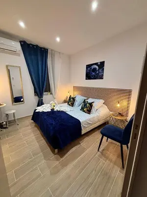 a bedroom with a large bed and a blue chair at La Saphir in Narbonne