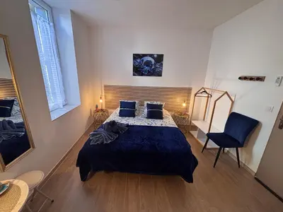 a bedroom with a bed and a chair and a mirror at La Saphir in Narbonne