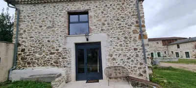 a stone building with a door and a bench at La Métairie du Château, Elie in Aussillon