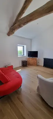 a living room with a red couch and a flat screen tv at Métairie du Château Berthe in Aussillon