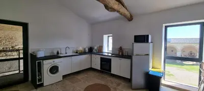 a kitchen with a refrigerator and a washer and dryer at Métairie du Château Berthe in Aussillon