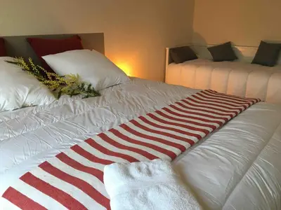 a white bed with a red and white blanket on it at Villa Et au milieu coule un ruisseau - Piscine, jacuzzi privé, boulodrome in Berlou
