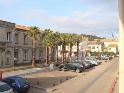 a street with cars parked in a parking lot with palm trees at Au cœur du village de Gruissan in Gruissan