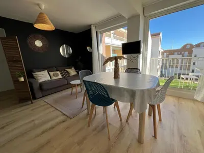 a dining table and chairs in a living room at Bel appartement avec piscine et vue bateaux in Gruissan