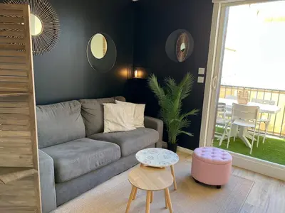 a living room with a couch and a table at Bel appartement avec piscine et vue bateaux in Gruissan