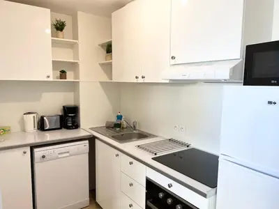 a kitchen with white cabinets and a sink at Bel appartement avec piscine et vue bateaux in Gruissan