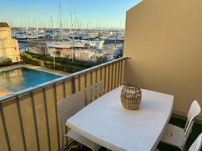 a table with a vase on a balcony with a harbor at Bel appartement avec piscine et vue bateaux in Gruissan