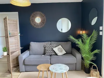 a living room with a gray couch and two mirrors at Bel appartement avec piscine et vue bateaux in Gruissan
