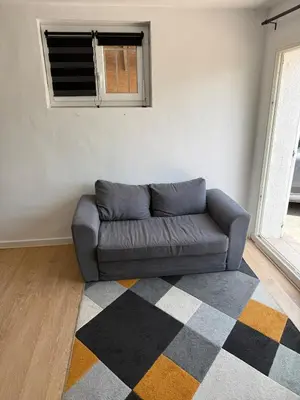 a couch in a living room with a window at Appartement indépendant climatisé Chez Amel & Rémi in Fabrezan