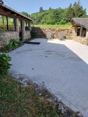 a driveway with two chairs in front of a stone building at La Bergerie Maison familiale in La Salvetat