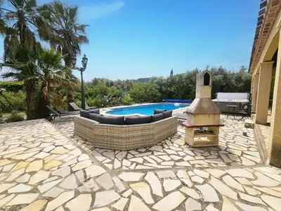 a patio with a couch and a fireplace next to a pool at La Cerisette in Félines-Minervois