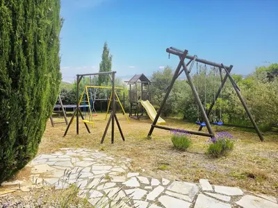 a playground with two swings and a swing set at La Cerisette in Félines-Minervois