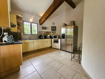 a large kitchen with stainless steel refrigerator and cabinets at La Cerisette in Félines-Minervois