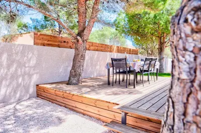 a table and chairs on a wooden deck with a tree at Villa Louise in Lapalme