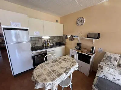 a small kitchen with a table and a refrigerator at Appartement 2 pièces - Port la Nouvelle PN010-18 in Port-la-Nouvelle