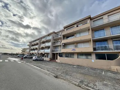 an apartment building with cars parked in front of it at Appartement 2 pièces - Port la Nouvelle PN010-18 in Port-la-Nouvelle