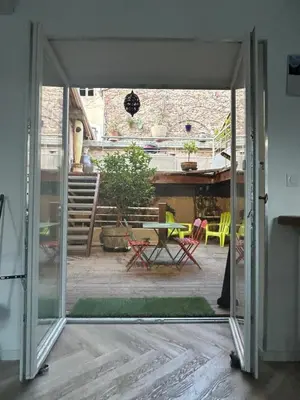 an open door to a patio with a table and chairs at Maison chaleureuse atypique in Saint-Chinian