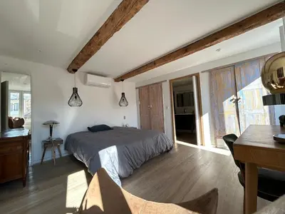 a bedroom with a bed and a desk and windows at Maison chaleureuse atypique in Saint-Chinian