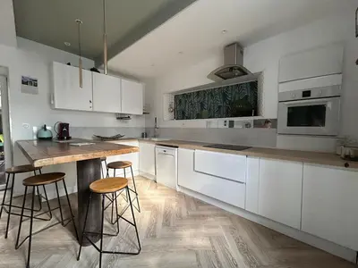 a kitchen with white cabinets and a wooden counter top at Maison chaleureuse atypique in Saint-Chinian