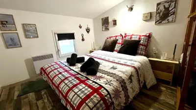 a bedroom with a bed with a red and white blanket at Appartement style chalet proche Cité Carcassonne & lac de la Cavayère in Trèbes