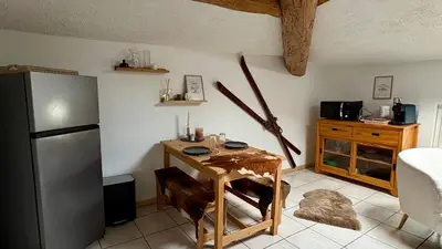 a kitchen with a small table and a refrigerator at Appartement style chalet proche Cité Carcassonne & lac de la Cavayère in Trèbes