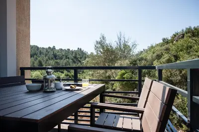 a wooden table and chair on a balcony with a view at Gîte au cœur des vignes, vue sur le Minervois in Bize-Minervois