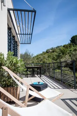 a patio with a table and chairs on a balcony at Gîte au cœur des vignes, vue sur le Minervois in Bize-Minervois