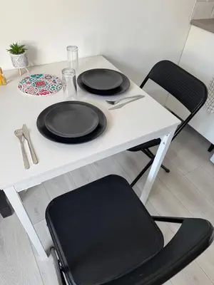 a white table with two black plates and a chair at La perle centrale - Studio in Limoux
