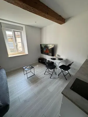 a white living room with a table and chairs at La perle centrale - Studio in Limoux