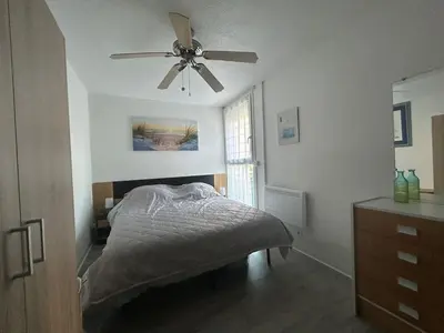 a bedroom with a bed and a ceiling fan at Le Ponant - Appartement proche du port et de la mer in Gruissan