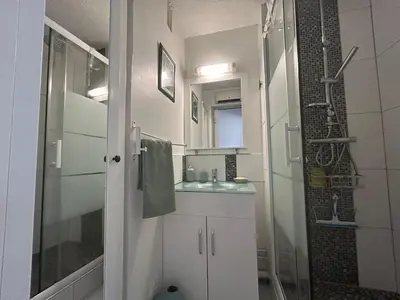 a white bathroom with a shower and a sink at Le Ponant - Appartement proche du port et de la mer in Gruissan