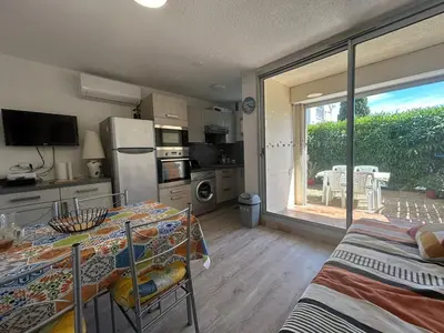 a kitchen with a table and a dining room with a window at Le Ponant - Appartement proche du port et de la mer in Gruissan