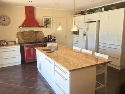 a kitchen with white cabinets and a red stove top oven at Villa privée Un vrai havre de paix in Limoux