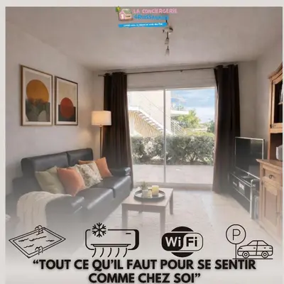 a living room with a couch and a large window at Résidence Les jardins du Phoebus Géolia Piscine Climatisation Parking By LCG in Gruissan