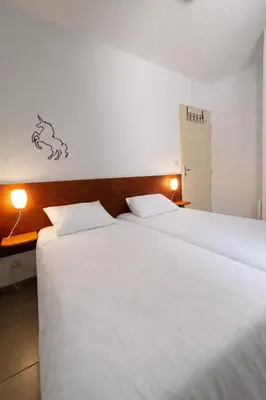 two beds in a hotel room with white sheets at Résidence Les jardins du Phoebus Géolia Piscine Climatisation Parking By LCG in Gruissan