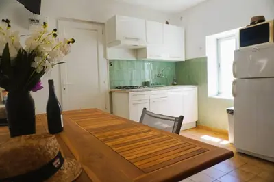 a kitchen with a table and a white refrigerator at La Dorade du port in Port-la-Nouvelle