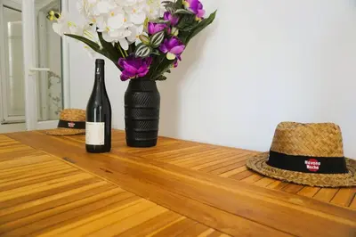 a bottle of wine and a vase with purple and white flowers at La Dorade du port in Port-la-Nouvelle