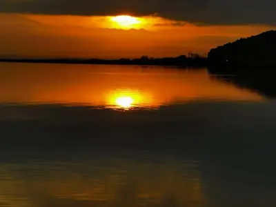 a sunset over a body of water with the sun setting at La Dorade du port in Port-la-Nouvelle