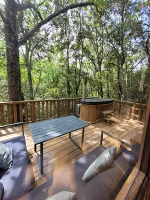 a wooden deck with a bench and a table and a grill at Cabane d'Oniria in Palaja